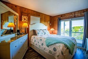 Une chambre à coucher avec un lit, des lampes de chevet, une commode, un miroir et une fenêtre donnant sur un beau paysage.
