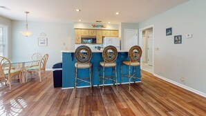 Une cuisine avec un îlot central bleu, des chaises en bois et une table à manger avec des chaises.