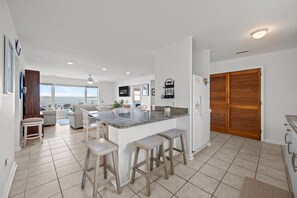 Uma cozinha moderna com uma ilha central, banquetas, frigorífico e armários de madeira.