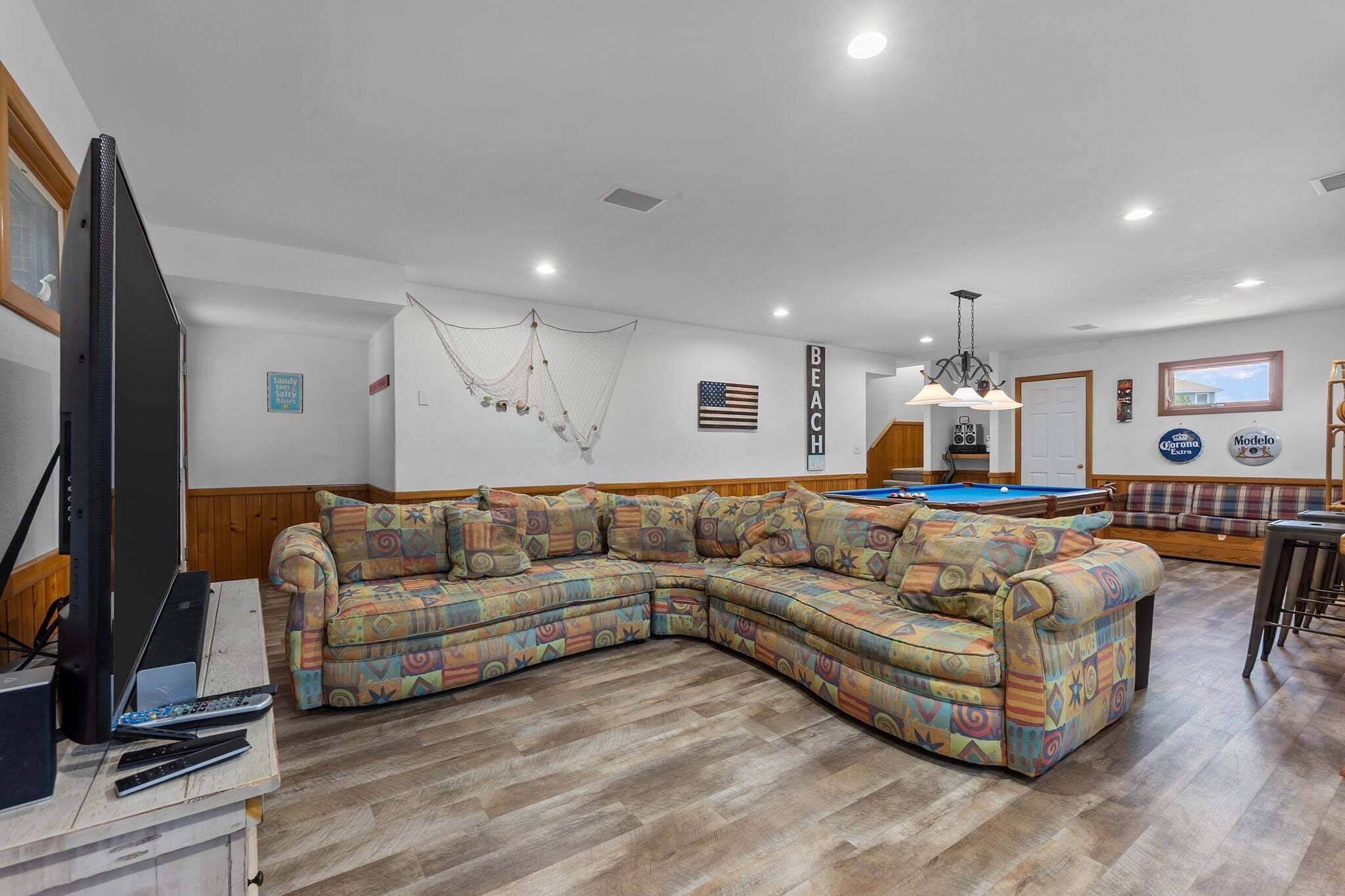 Una sala de estar con mesa de billar, sofá modular, televisor y hamaca.