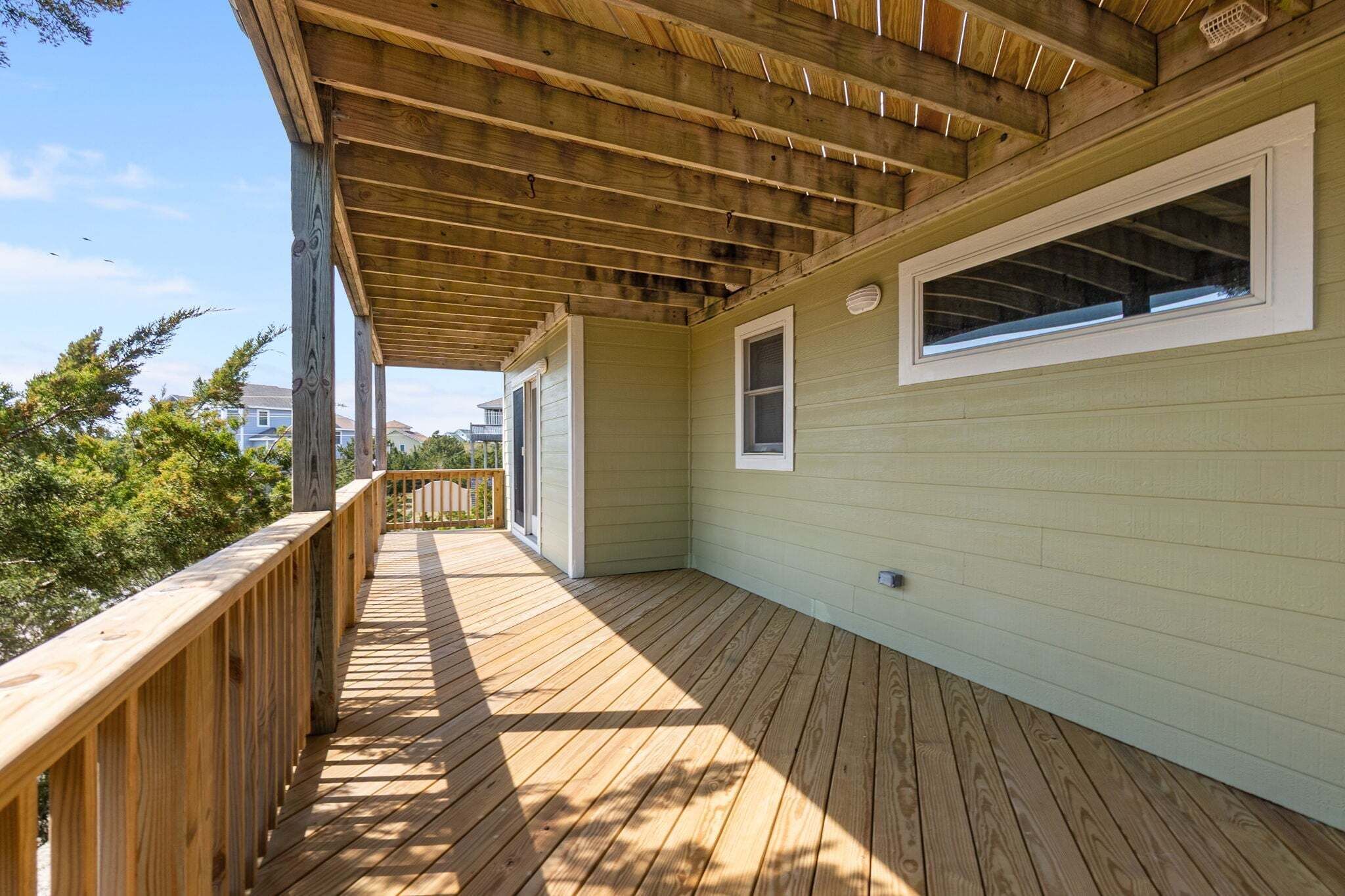 A wooden deck with a covered area, a window, and a door.