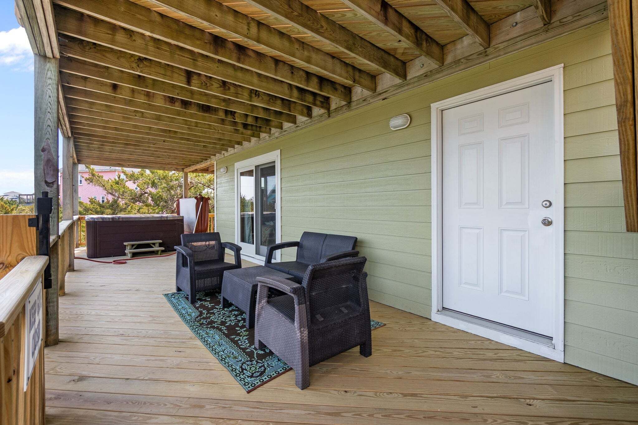 Eine überdachte Veranda mit Holzterrasse, Whirlpool und Gartenmöbeln.