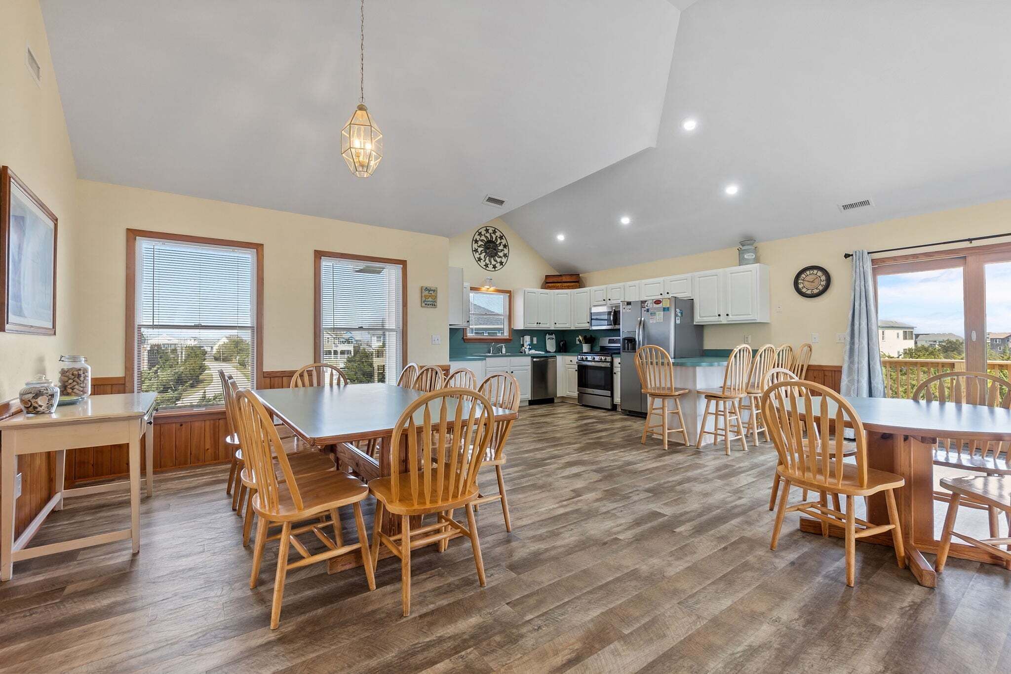 A spacious kitchen with wooden cabinets, a dining area with a large table and chairs, and a view through the windows.