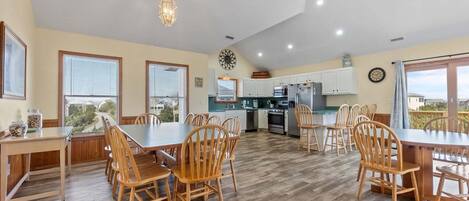 A spacious kitchen with wooden cabinets, a dining area with a large table and chairs, and a view through the windows.