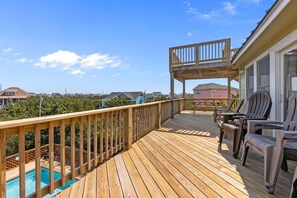 A wooden deck with a pool, outdoor seating, and a covered area.