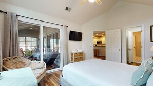 A spacious bedroom with a large bed, a sofa, and a sliding glass door leading to a balcony.