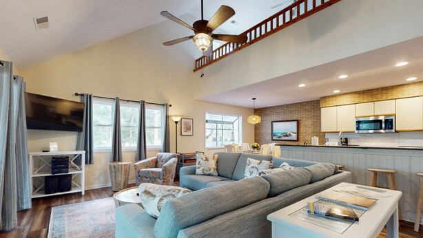 A spacious living room with a grey sofa, a white coffee table, and a ceiling fan.