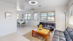 A modern living room with a leather sofa, a wooden coffee table, and a dining area with a table and chairs.