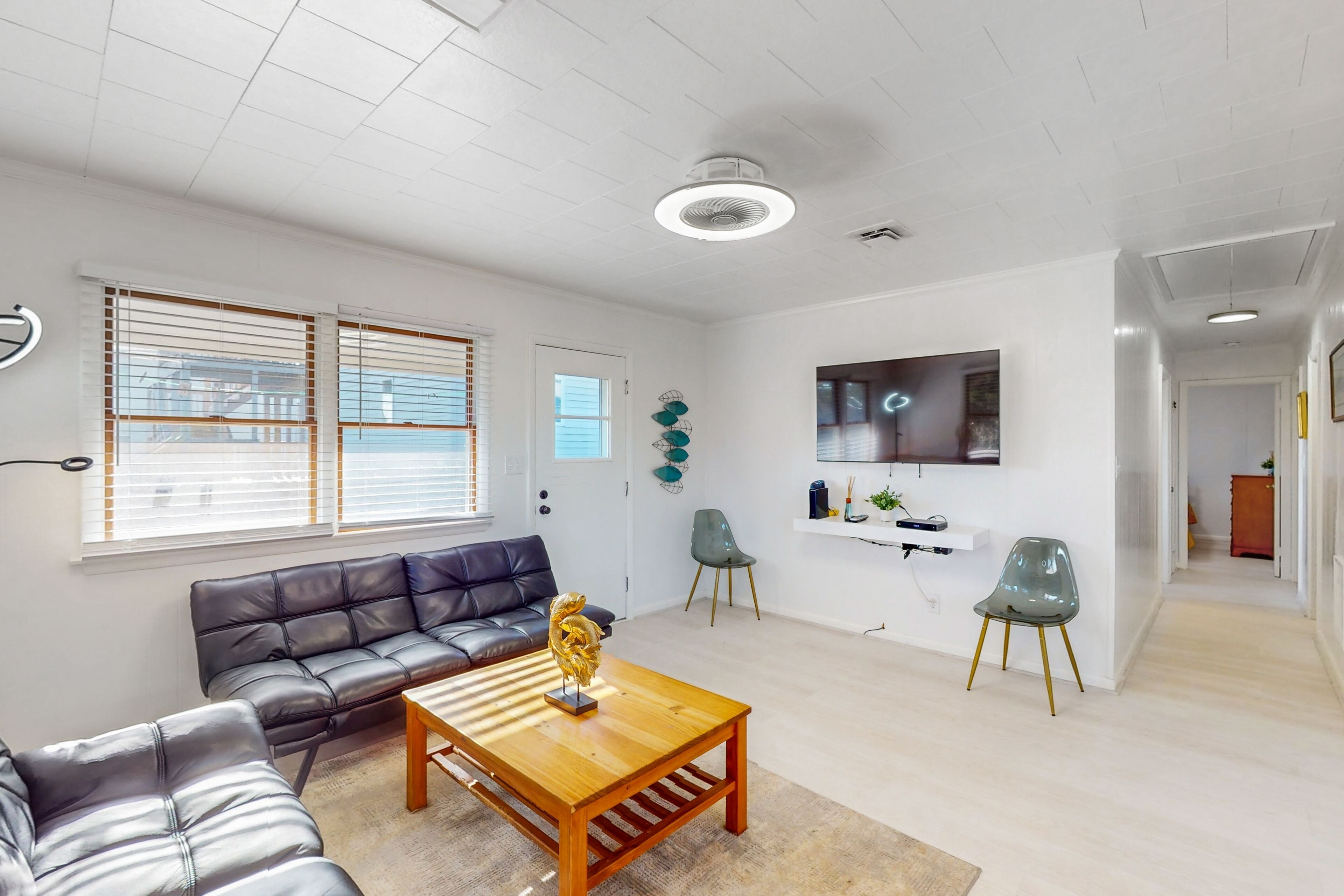 Ein modernes Wohnzimmer mit Ledersofa, Holztisch und Wandfernseher.