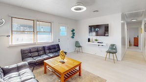 A modern living room with a leather sofa, wooden coffee table, and a TV mounted on the wall.