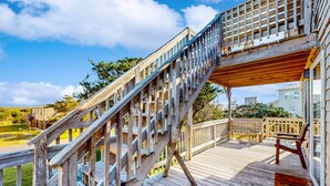 A wooden deck with a staircase leading to an upper level.