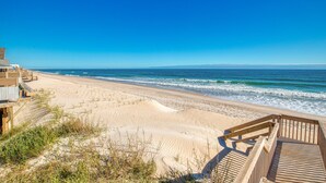 A beach with a wooden boardwalk leading to a sandy shore, overlooking the ocean. - Oceanfront home with private beach access & outdoor shower - dog-friendly (Surf City)