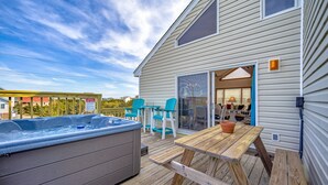 Une terrasse en bois avec un jacuzzi, des sièges d’extérieur et une vue sur les environs.