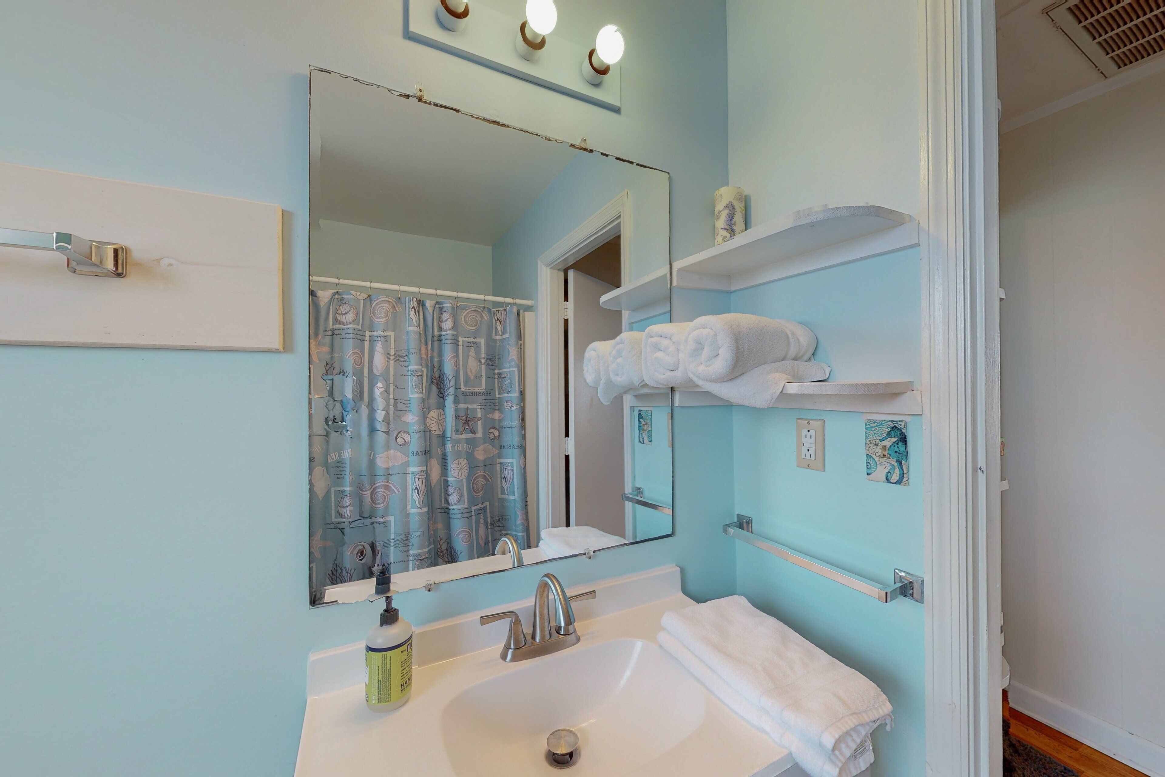 A bathroom with a sink, mirror, and towel rack.