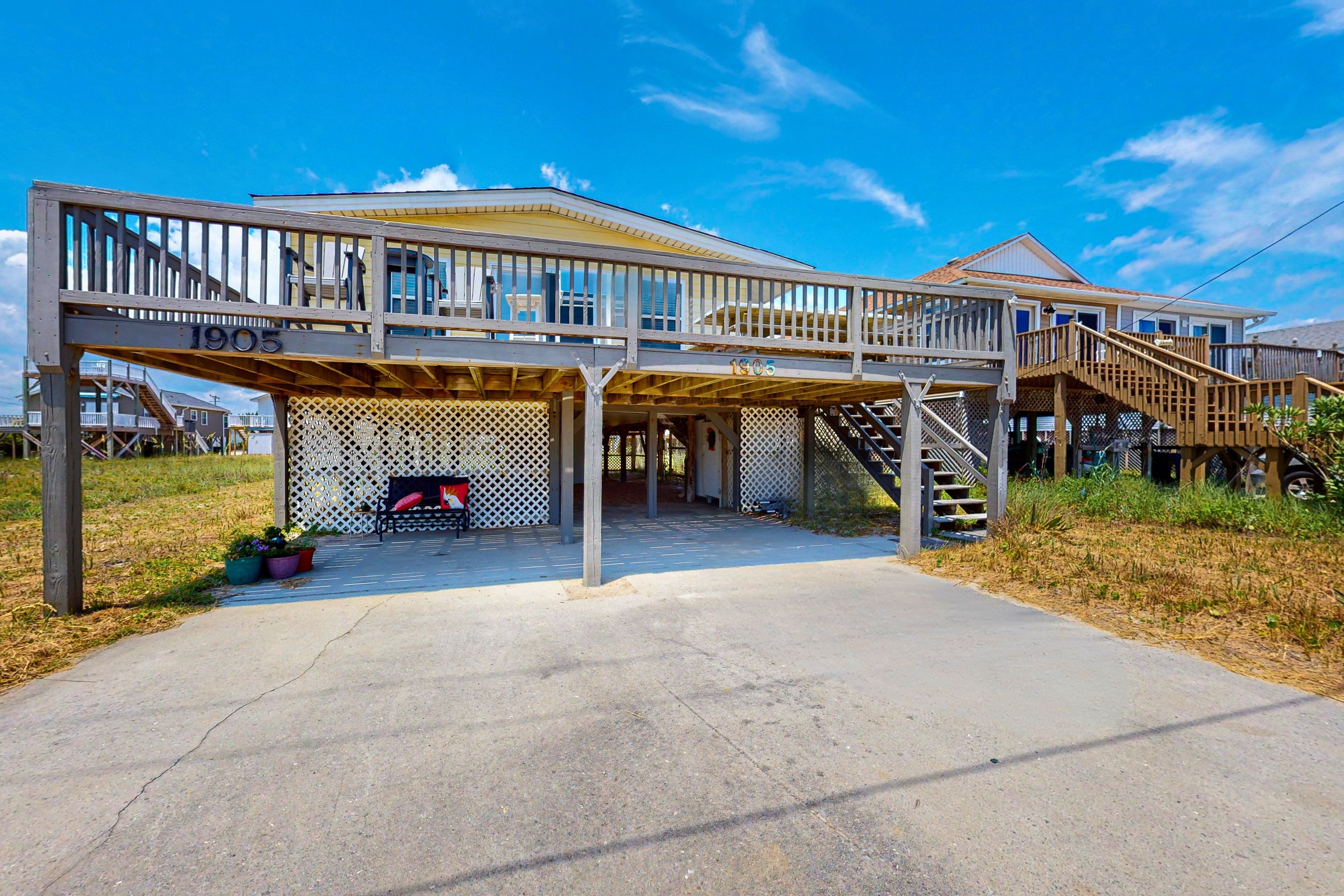 A two-story wooden structure with a covered patio area and a staircase leading to an upper level.