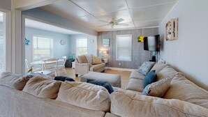 A spacious living room with a large sectional sofa, a dining area with a table and chairs, and a ceiling fan. - Oceanview home with direct beach access just across the street (Surf City)