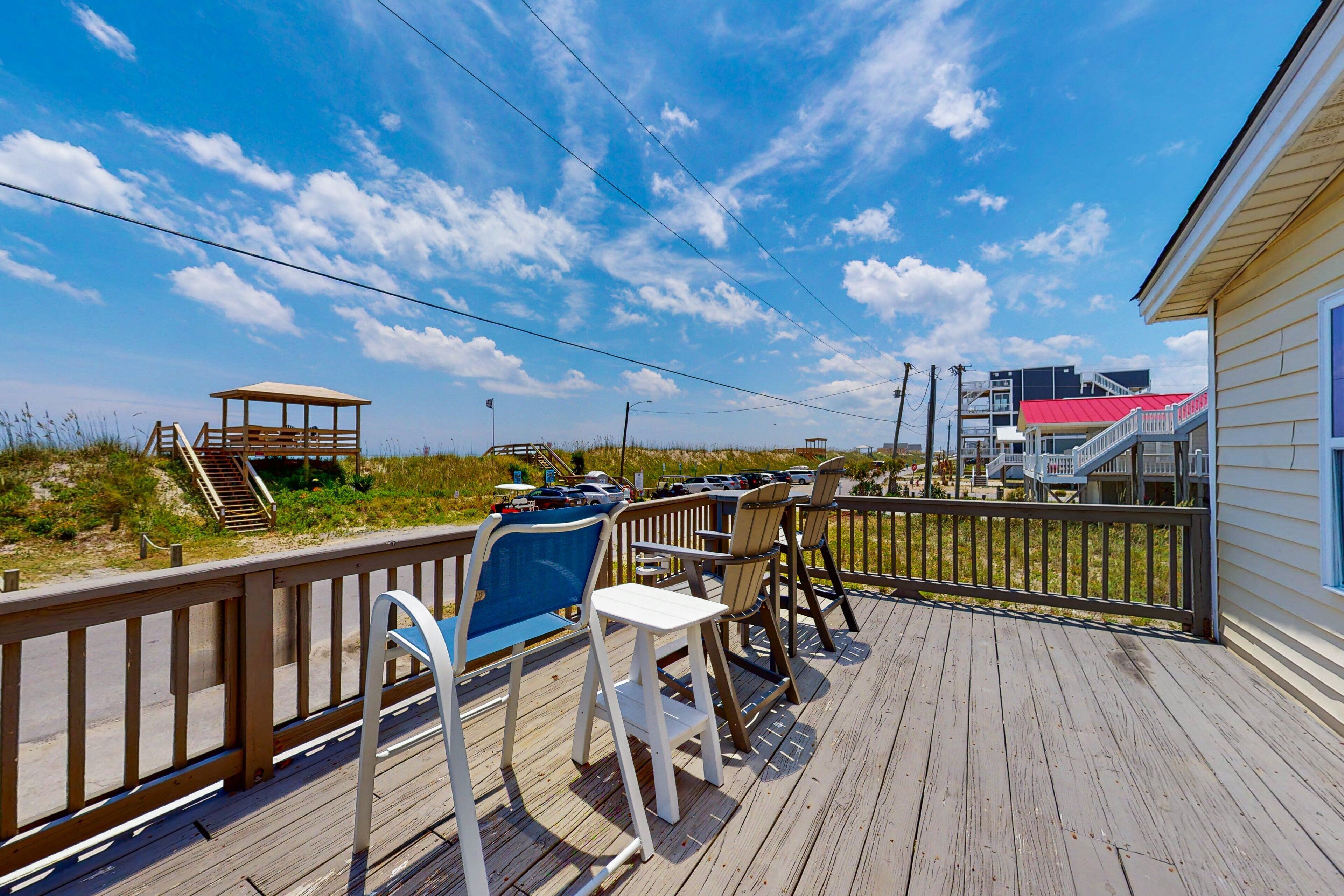 A wooden deck with outdoor seating, a beach view, and a lifeguard tower.