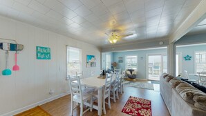 A dining area with a white table and chairs, a ceiling fan, and a view to the outside. - Oceanview home with direct beach access just across the street (Surf City)