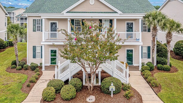 A two-story building with a balcony, a front entrance, and a small tree in the front yard. - Coral Hideaway: Balcony | Pool | Dog Friendly (Sunset Beach)
