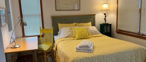A neatly arranged bedroom with a bed, a desk, and a chair.