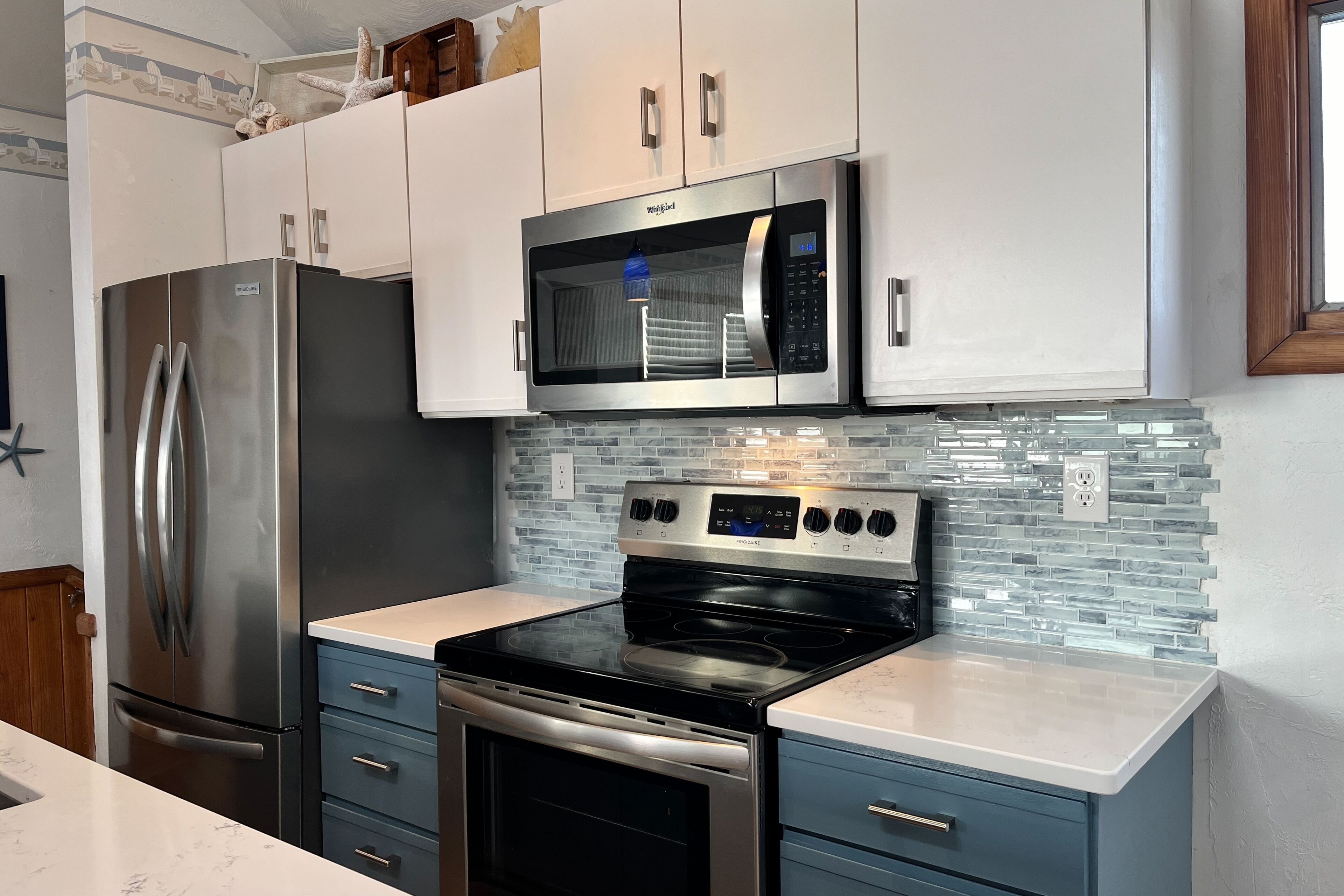 A modern kitchen with stainless steel appliances, a microwave, and a glass-tiled backsplash.