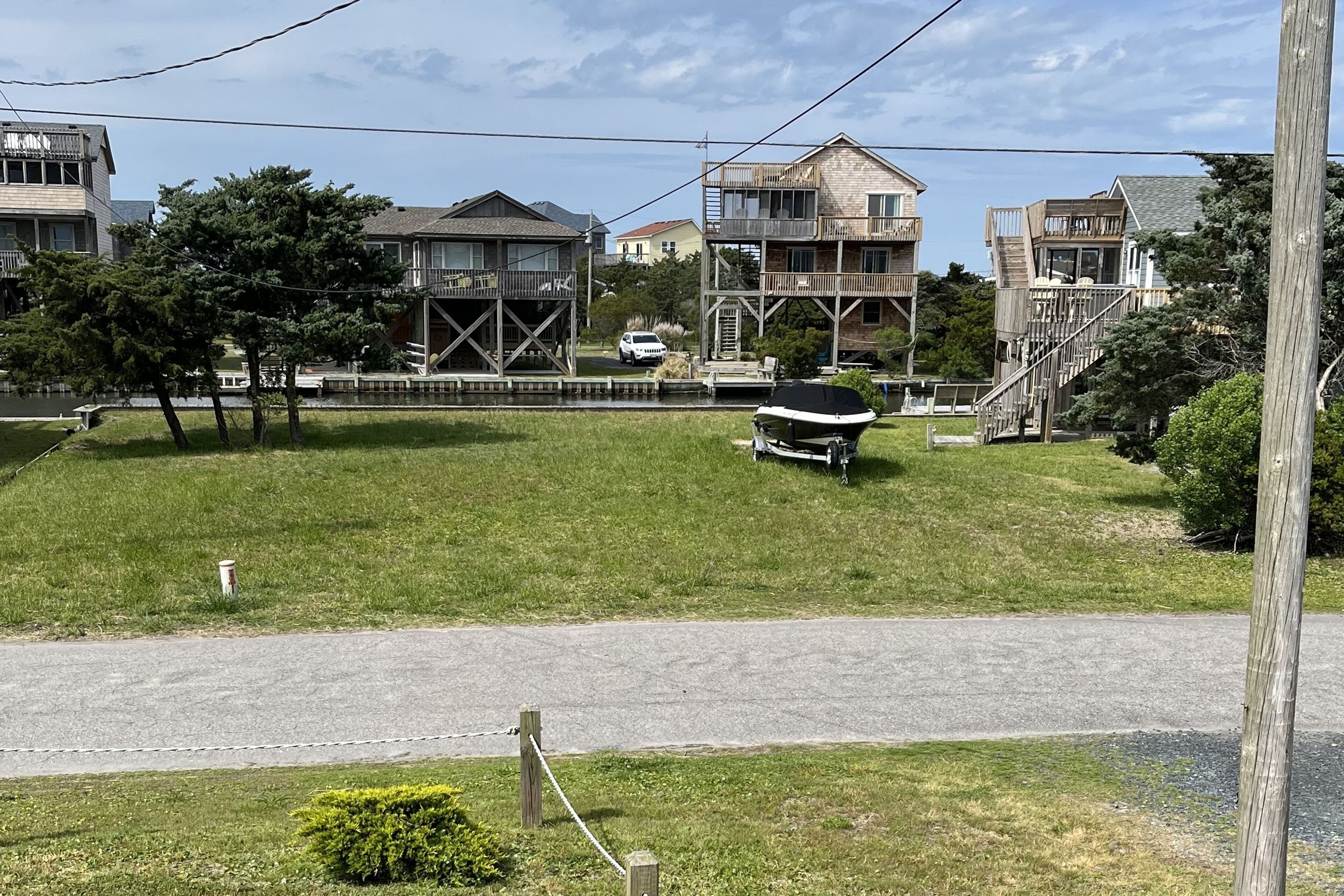 A residential area with houses, a grassy field, a dock, and a road.