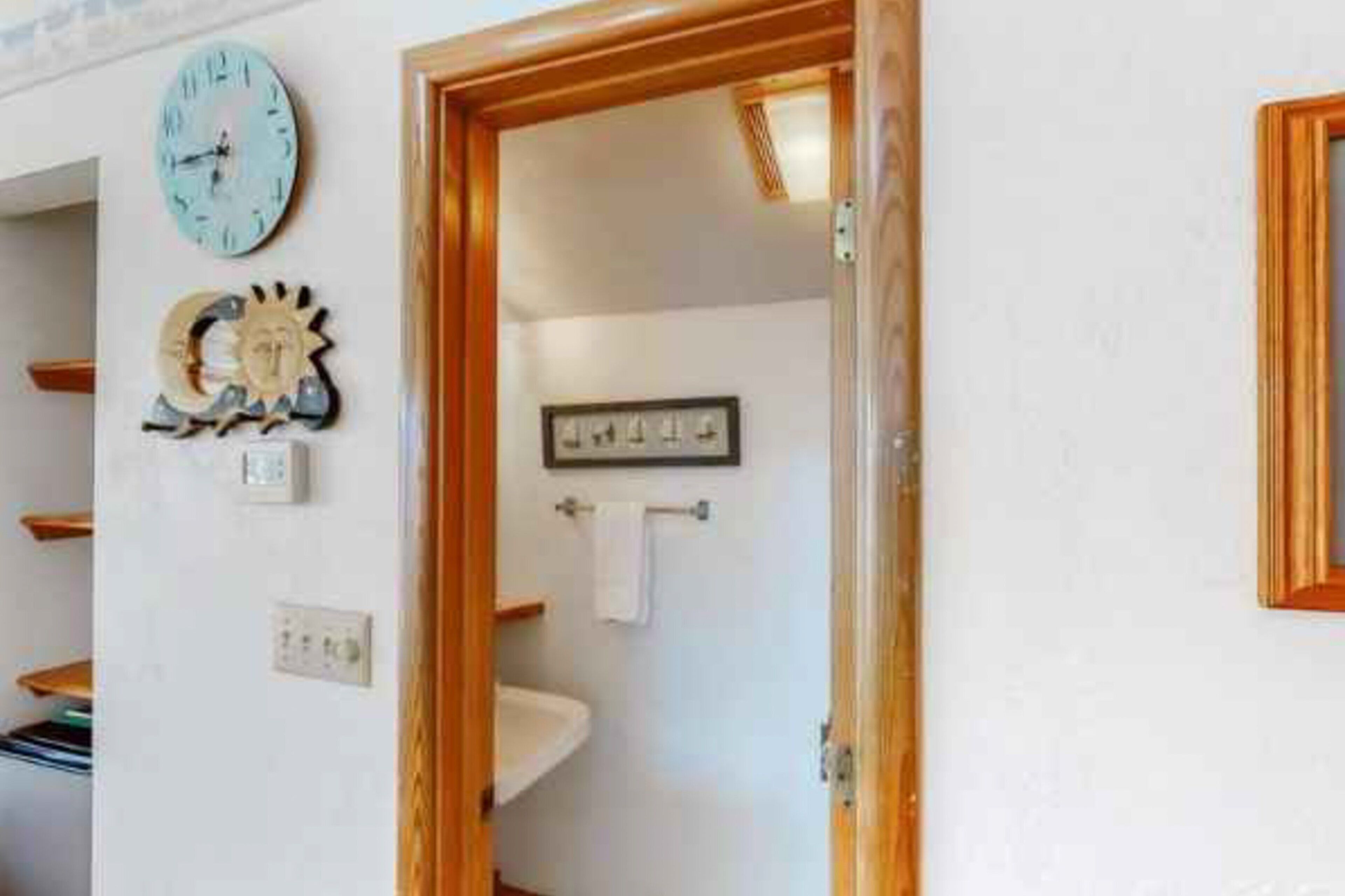A bathroom with a sink, a clock, and a towel rack.