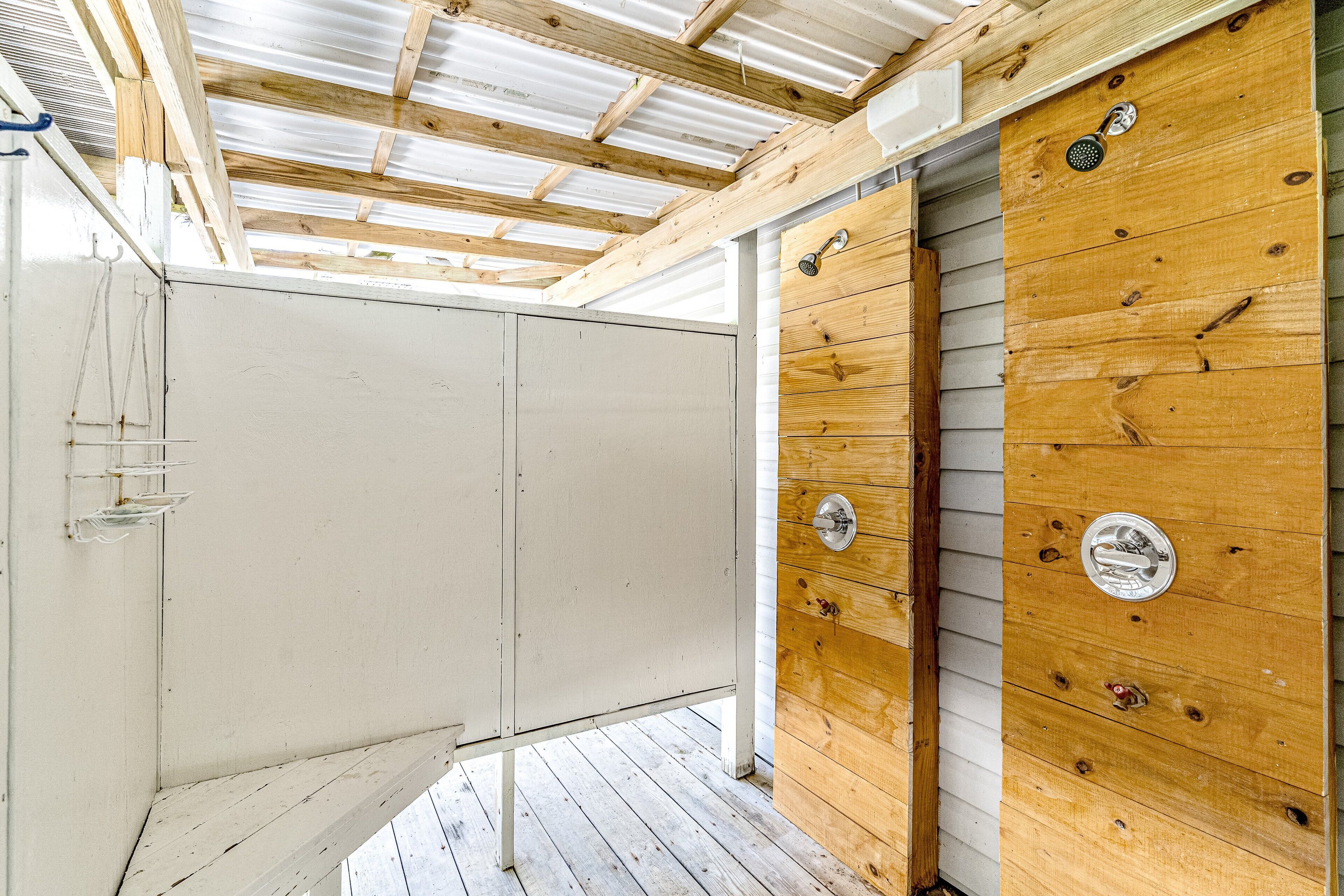 A room with a wooden ceiling, a white wall, and a wooden door with a metal handle.