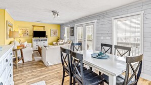 A dining area with a white table, black chairs, and a blue tray. - Home near the beach with balconies, outdoor shower, grill, beach gear, W/D, & AC (Sunset Beach)