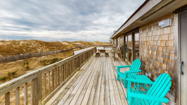 A wooden deck with turquoise chairs and a table, overlooking a beach with dunes. - Oceanfront, Dog-Friendly House w/ Free WiFi, Central AC, Private W/D, Ocean View (Hatteras)
