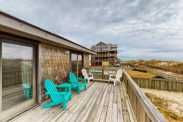 A wooden deck with turquoise Adirondack chairs and a glass door leading to a room. - Oceanfront, Dog-Friendly House w/ Free WiFi, Central AC, Private W/D, Ocean View (Hatteras)