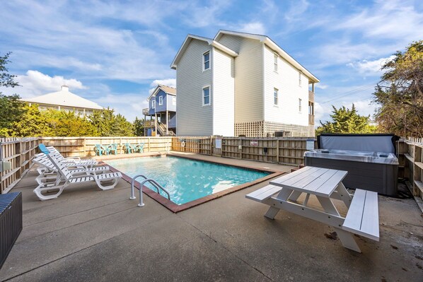 A swimming pool with lounge chairs and a hot tub, surrounded by a wooden fence and a building with a sloped roof. - Dog-friendly home with private pool, hot tub, fast WiFi & AC (Avon)