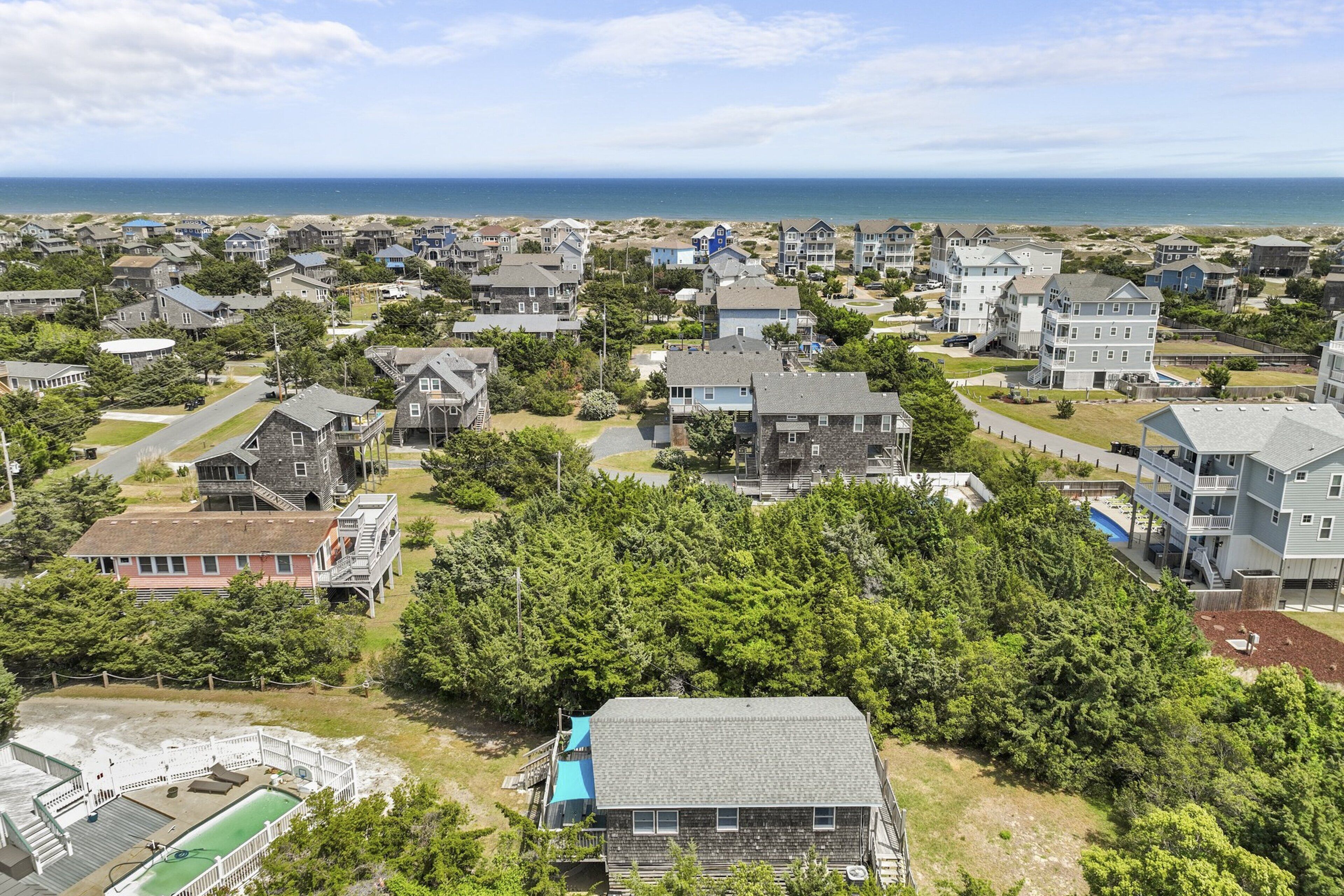A coastal residential area with houses, a playground, and a view of the ocean.