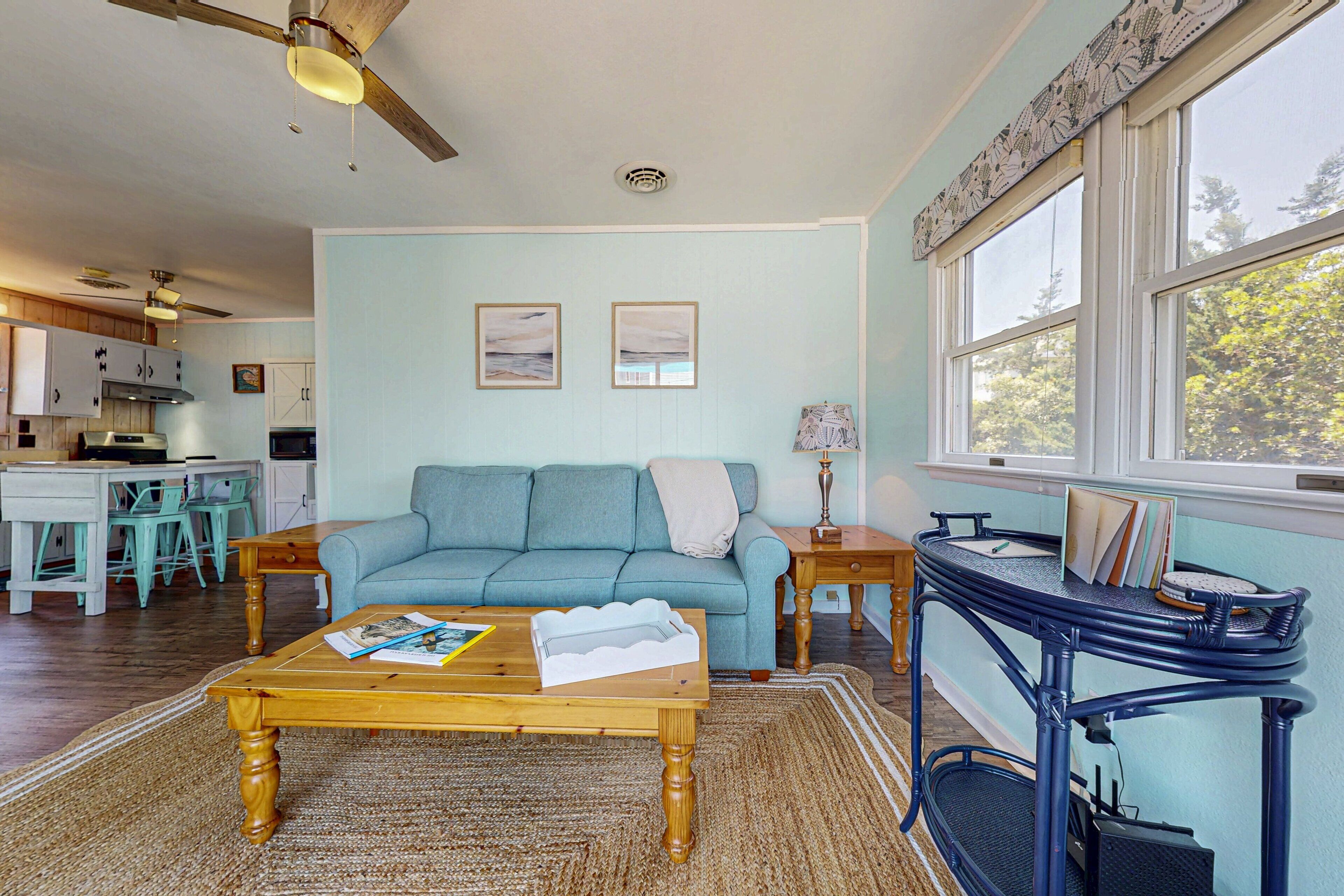 A living room with a blue sofa, wooden coffee table, and a blue side table with books.
