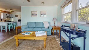 A living room with a blue sofa, wooden coffee table, and a blue side table with books. - Charming Family Getaway in Salvo with A/C, Full Kitchen, and Gas Grill (Salvo)