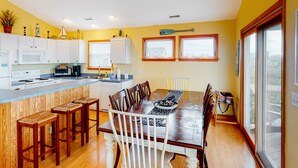 A kitchen with white cabinets, a wooden island with stools, and a dining table with chairs. - Lovely home with private pool, decks, amazing ocean view, & W/D (Hatteras)