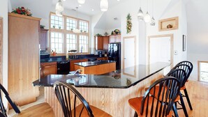A modern kitchen with wooden cabinets, a central island, and pendant lighting. - Lakefront, dog-friendly home with W/D, private pool & hot tub - close to beach (Avon)