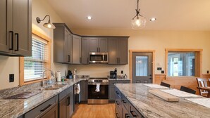 A modern kitchen with granite countertops, stainless steel appliances, and wooden flooring. - Elkmont Mountain Splash • Indoor Pool & Views (Sevierville)