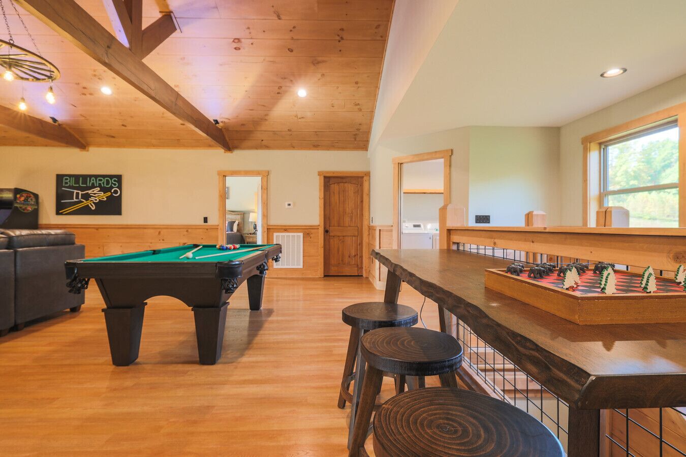 Une salle de billard équipée d’une table de billard, de tabourets et d’une table de baby-foot.