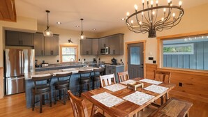 A spacious kitchen with a large island, wooden bar stools, and a chandelier. - Elkmont Mountain Splash • Indoor Pool & Views (Sevierville)