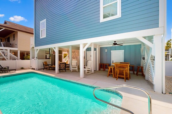 A residential pool area with a blue house, outdoor furniture, and a covered patio. - Seabirds: Ocean-view home near beach with private pool, outdoor shower, & elevator (Sunset Beach)