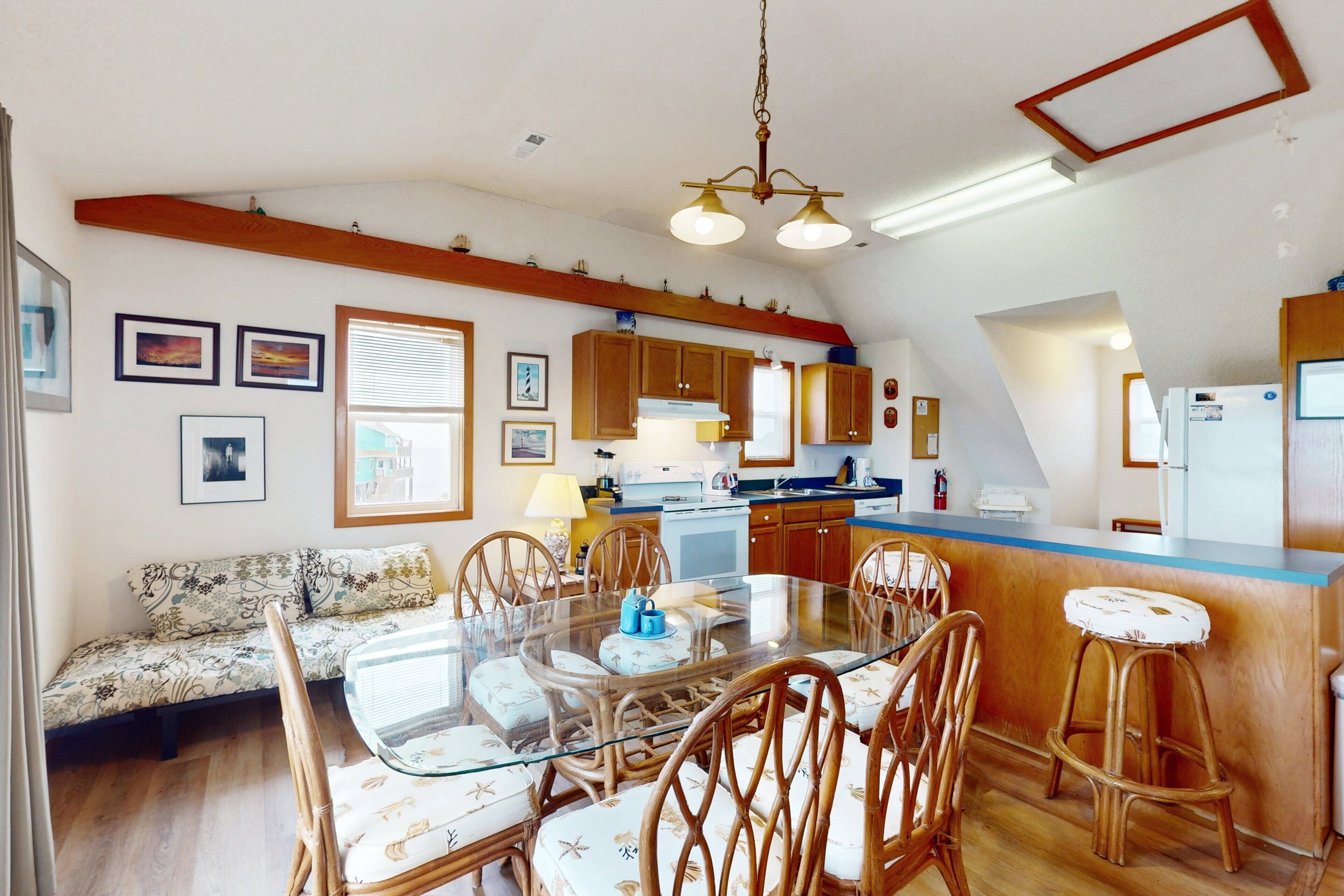 A spacious kitchen with wooden cabinets, a central island with stools, and a dining table with chairs.
