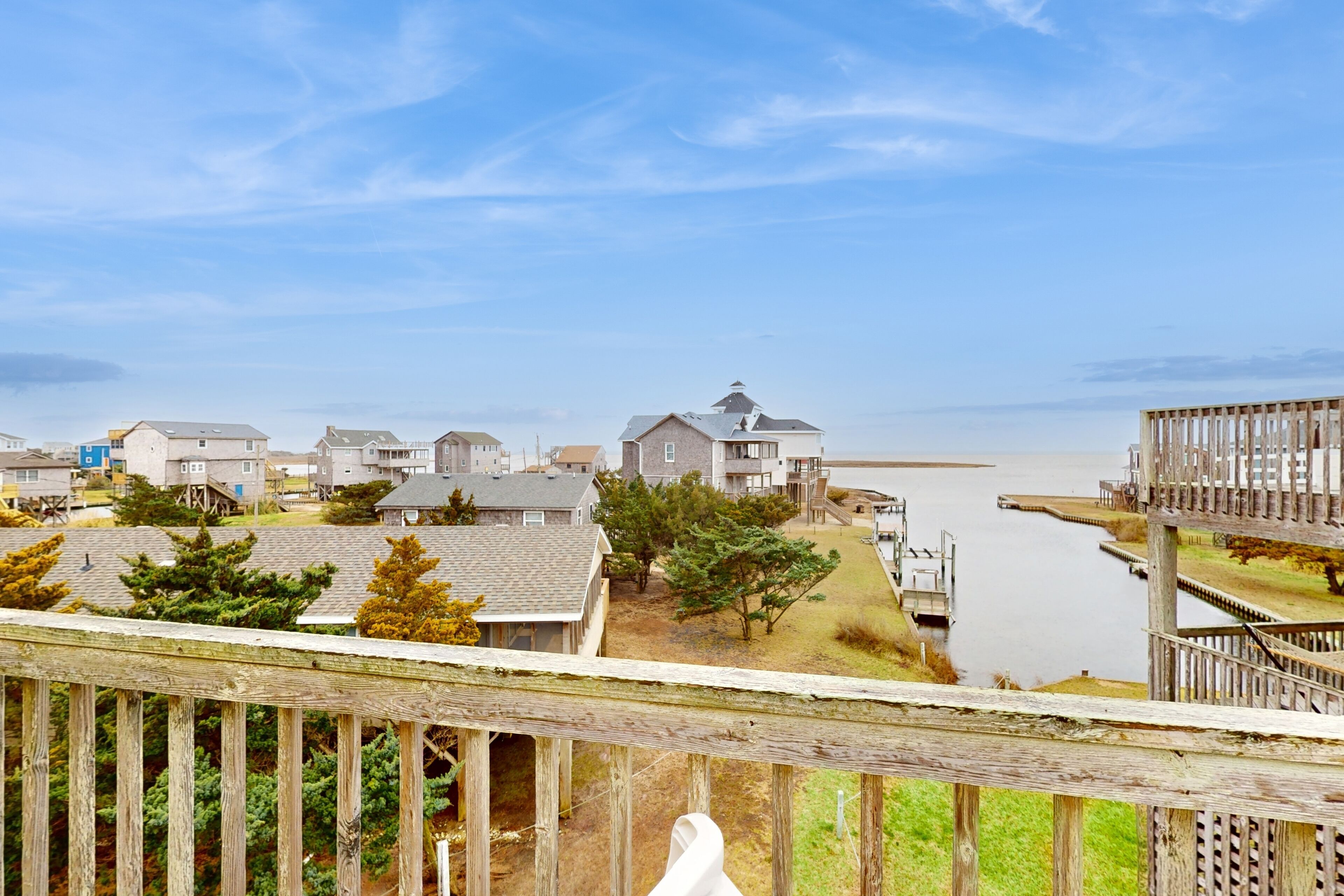 A residential area with houses, a wooden dock, and a clear view of the water.