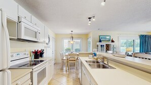 Une cuisine moderne avec des meubles blancs, un four à micro-ondes encastré, une cuisinière et un grand îlot central doté d’un évier.