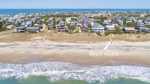 Vue aérienne d’un quartier résidentiel situé sur la côte, avec accès à la plage.