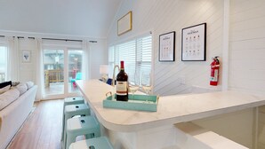Une cuisine moderne avec un coin bar, comprenant une bouteille de vin et des verres sur un plateau, un menu de cocktails encadré et un extincteur fixé au mur.