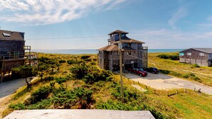 Un bâtiment situé sur la côte, doté d’une plateforme d’observation, entouré de végétation et surplombant un ciel dégagé.