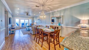 A spacious kitchen with a granite countertop, wooden dining table, and chairs. - Open, beautiful ocean-view home with pool, hot tub & lanai - snowbird-friendly (Rodanthe)