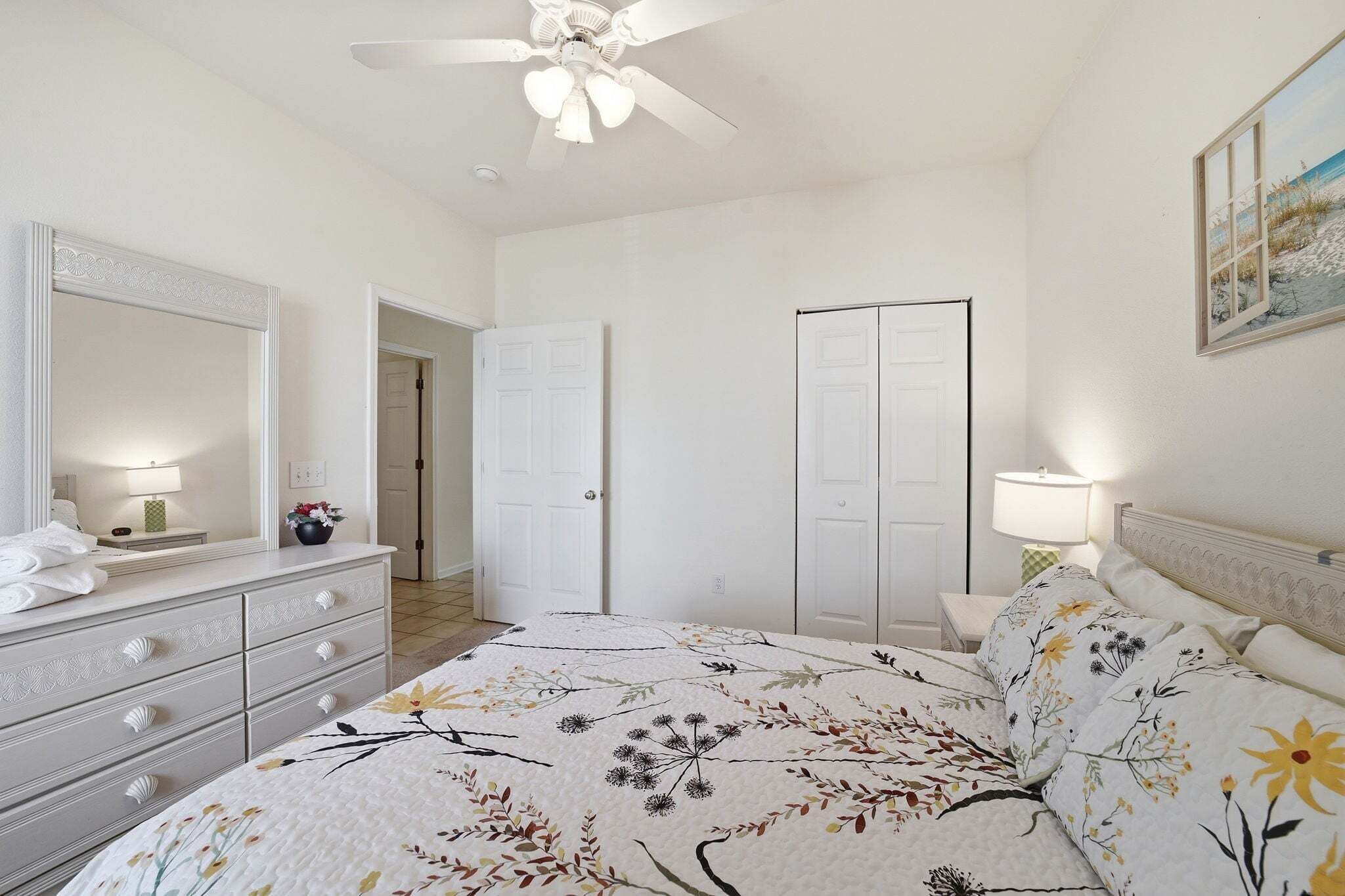 Un dormitorio con cama, cómoda, espejo y ventilador de techo.