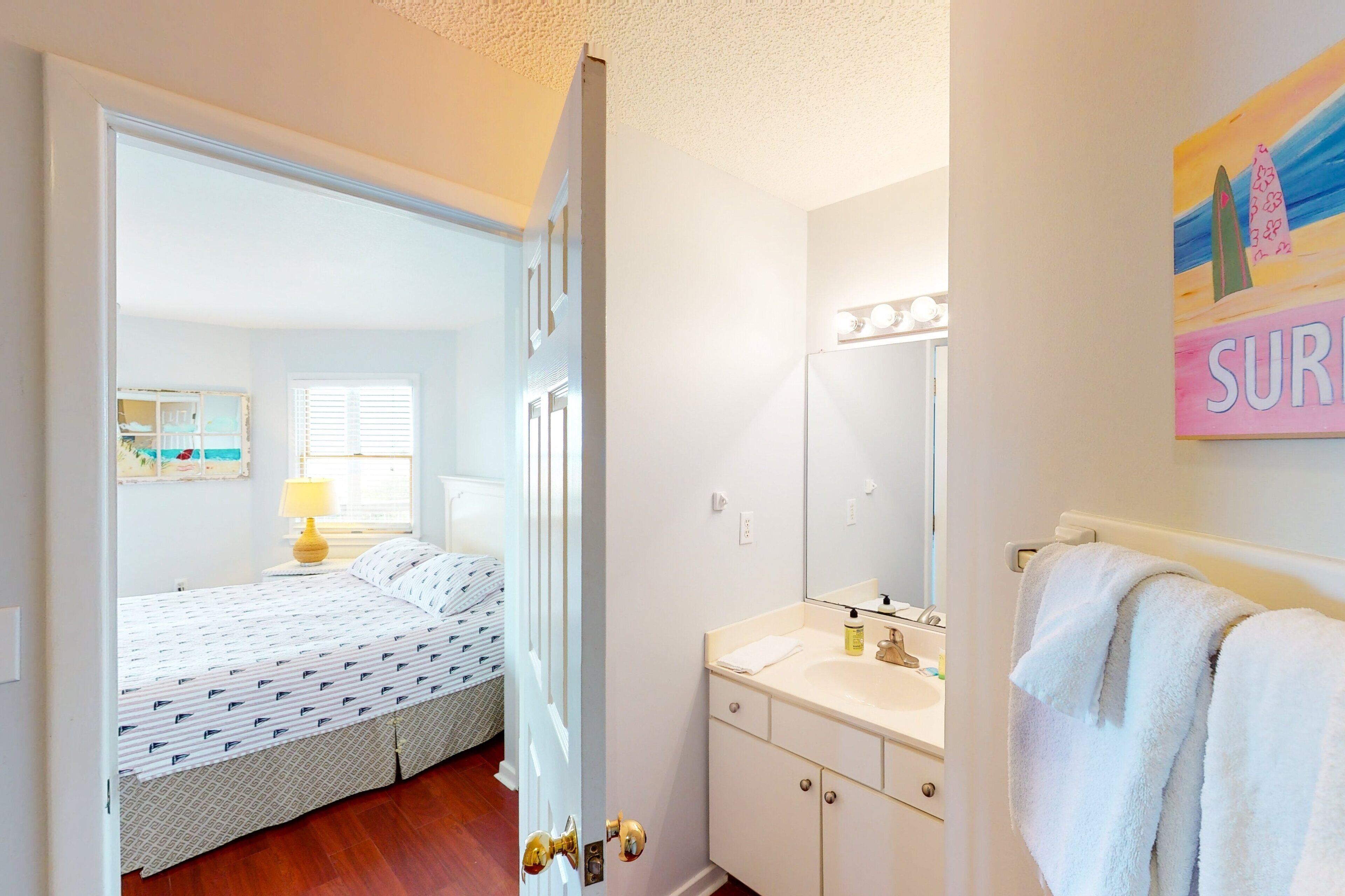 A bedroom with a bed, a bedside table with a lamp, and a window with blinds.